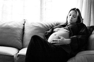 B&W photograph of pregnant woman sitting on couch
